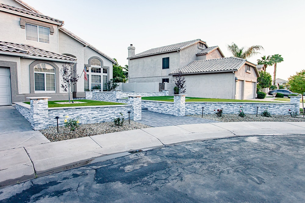Front Yard Landscaping with Stone Wall, Paver Driveway, and Green Lawn