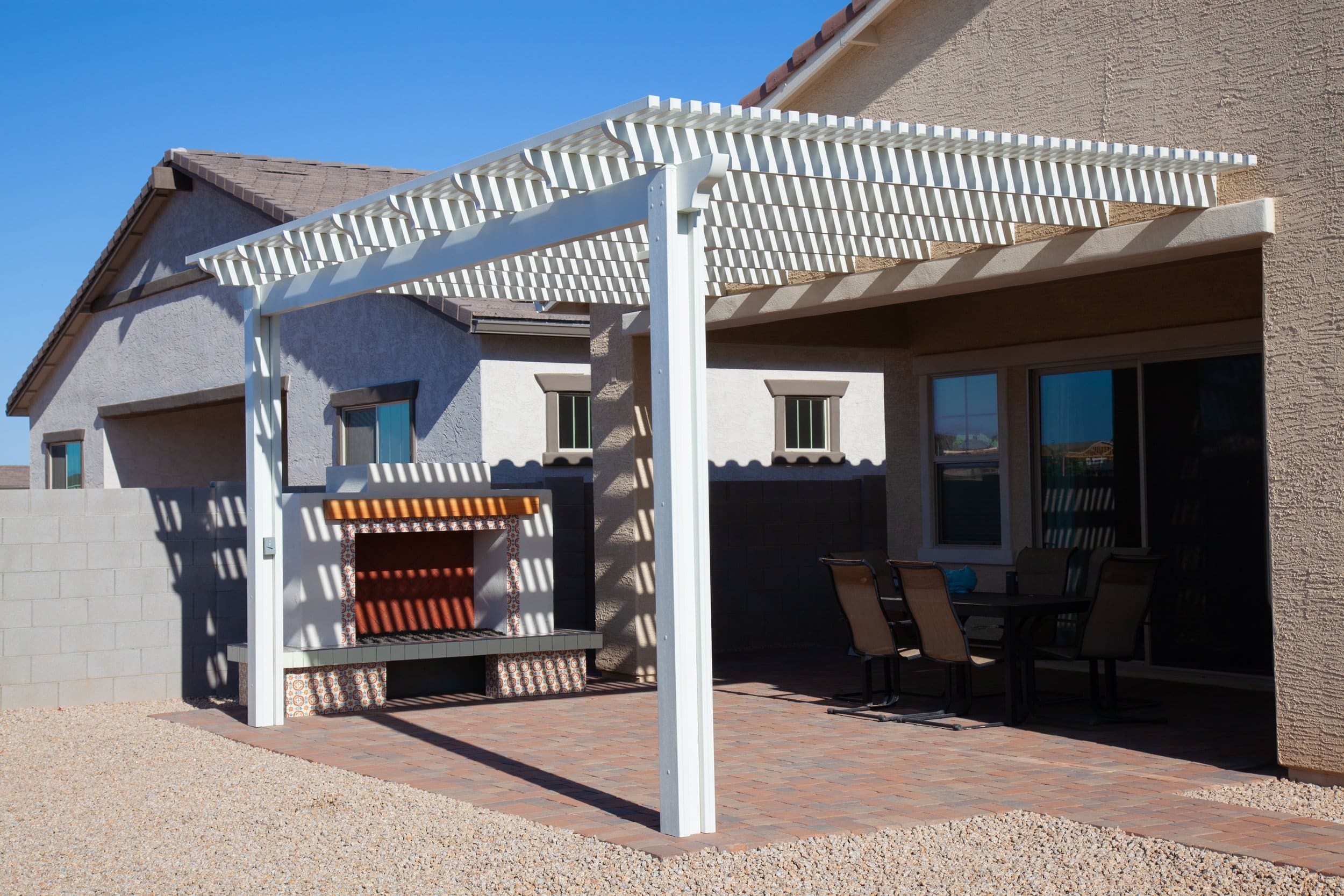 Backyard patio with white pergola, outdoor seating, and a built-in BBQ area
