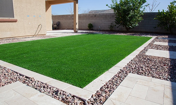 Low-Maintenance Backyard Design Featuring Artificial Turf and Stone Edging
